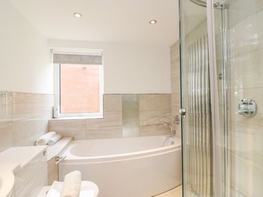 A bathroom with a bathtub shower toilet and window at Newton's Cove View in Weymouth