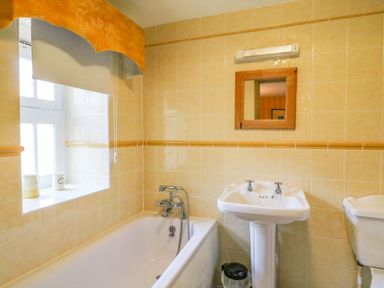 A bathroom with a bathtub sink mirror and window at The Oast House Brewers Quay Harbour
