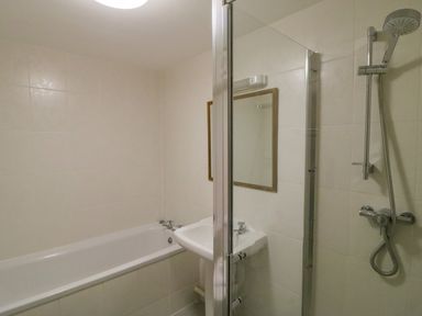 A bathroom with a bathtub a sink a mirror and a glass shower screen at The Oast House Brewers Quay Harbour