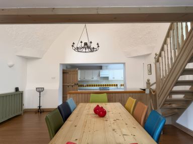 A dining room with a wooden table and colorful chairs at The Oast House in Brewers Quay Harbour