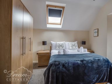 A bedroom with a double bed bedside tables lamps a wardrobe and a skylight window at Old Boathouse Weymouth