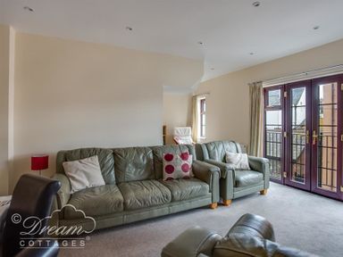 A living room with green sofas near purple framed glass doors at Old Boathouse in Weymouth