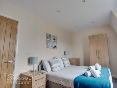 A bedroom with a double bed bedside tables lamps and a wardrobe at Old Boathouse Weymouth
