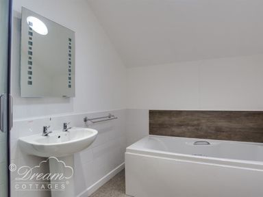 A bathroom with a bathtub and a sink under a wall mirror at Old Boathouse in Weymouth