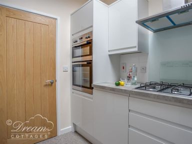 A kitchen with wooden door double oven white cabinets gas stove and drinks on the counter at Old Boathouse in Weymouth