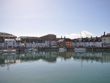 A harbor with boats docked and buildings along the waterfront at The Old Boathouse in Weymouth