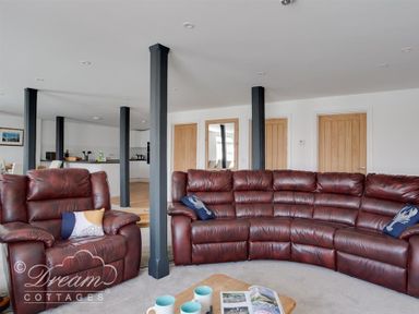 A living room with brown leather sofas and wooden doors at Old Coastguard Apartment 2 in Weymouth