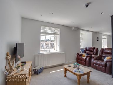 A living room with two leather recliner chairs a wooden coffee table a wall mounted television and a window at Old Coastguard Apartment 2 in Weymouth
