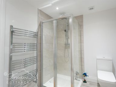 A bathroom with a glass shower enclosure a wall-mounted towel radiator and a toilet at Old Coastguard Apartment 2 in Weymouth