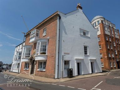 A street corner with buildings including one with red brick and bay windows at Old Coastguard Apartment 2 in Weymouth