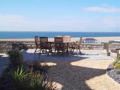 An outdoor patio with a table and six chairs overlooking the ocean at The Old Portland Courthouse in Portland
