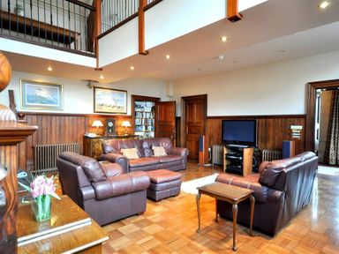 A living room with brown leather sofas a television and wooden paneling at The Old Portland Courthouse in Portland