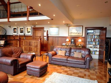A living room with brown leather sofas a wooden bookshelf and framed pictures at The Old Portland Courthouse in Portland