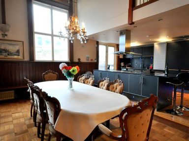 A dining table with a white tablecloth and flowers in a vase next to a kitchen with an island and bar stools at The Old Portland Courthouse in Portland