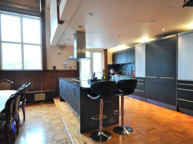 A kitchen with a central island and black bar stools next to a dining table at The Old Portland Courthouse in Portland