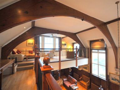 A two-level living room with wooden beams and railings with sofas on both levels at The Old Portland Courthouse in Portland