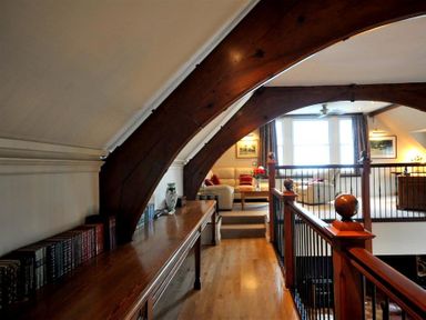 A hallway with wooden beams and a railing leading to a living area with sofas and a coffee table at The Old Portland Courthouse in Portland