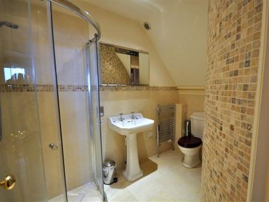 A bathroom with a curved glass shower enclosure a pedestal sink a toilet with a dark seat and tiled walls at The Old Portland Courthouse in Portland