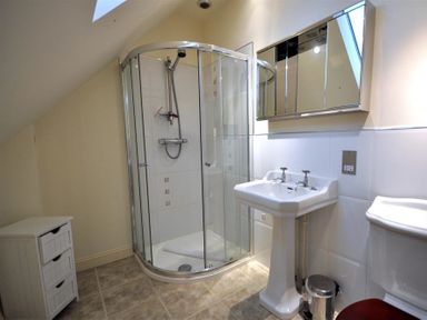 A bathroom with a corner shower stall a pedestal sink a mirrored cabinet a small white drawer unit and a toilet at The Old Portland Courthouse in Portland
