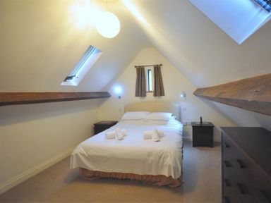 A bedroom with a double bed two bedside tables a chest of drawers and skylight windows at The Old Portland Courthouse in Portland
