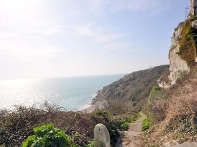 A coastal path leading down a cliffside with the sea and rocky coastline in view at The Old Portland Courthouse in Portland