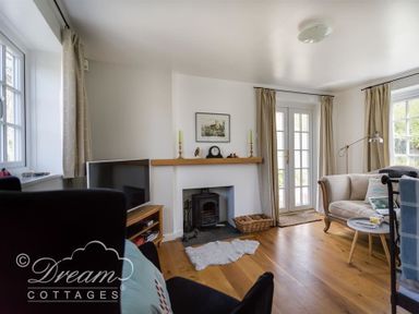A living room with a fireplace a television curtains and seating at The Old Reading Room in Langton Herring