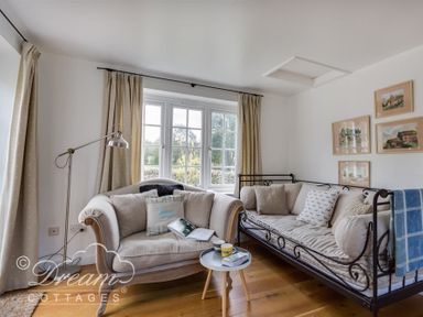 A living room with two sofas a small round table and paintings on the wall at The Old Reading Room in Langton Herring