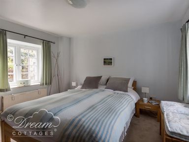 A bedroom with a double bed and two windows with green curtains at The Old Reading Room in Langton Herring