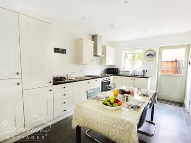 A kitchen with white cabinets black countertops a dining table with a yellow tablecloth and fruit bowl at Olympic Cottage in Portland