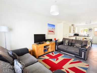A living room with two sofas a television on a wooden stand and a Union Jack rug at Olympic Cottage in Portland