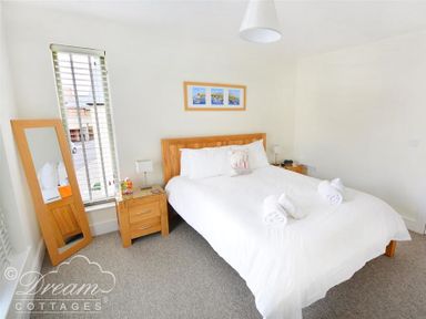 A bedroom with a bed with white bedding two nightstands a floor mirror and a window with blinds at Olympic Cottage in Portland