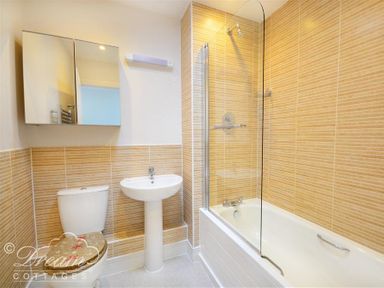 A bathroom with a toilet a pedestal sink a bathtub with shower and a wall-mounted cabinet at Olympic Cottage in Portland