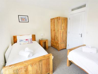 A bedroom with two single beds a wooden wardrobe and a small wooden side table with a lamp at Olympic Cottage in Portland