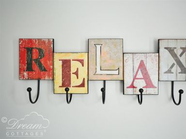 A wall-mounted coat rack with hooks and letters spelling relax at Olympic Cottage in Portland
