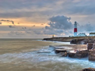A coastline with rocks and a lighthouse at Olympic Cottage in Portland