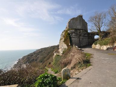 A coastal view with a stone path leading to a castle ruin on a cliffside at Olympic Cottage in Portland