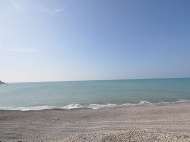 A view of a pebble beach with ocean waves under a clear sky at Olympic Cottage in Portland