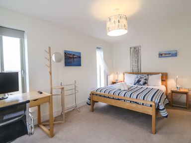 A bedroom with a wooden bed desk chair coat stand and two nightstands at Osprey House Portland