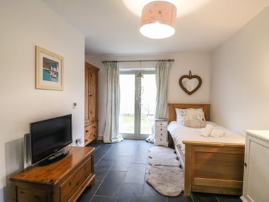 A bedroom with a single bed a wooden dresser a wardrobe a chest of drawers a wall mirror and a television at Osprey House Portland