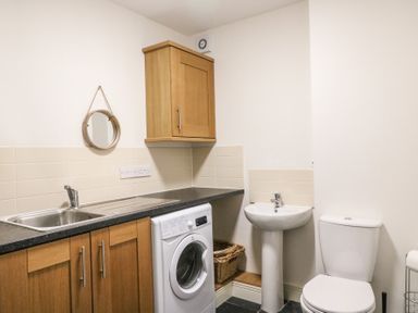 A utility room with sink washing machine toilet and a small wall mirror at Osprey House Portland