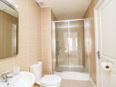 A bathroom with a sink, mirror, toilet, shower with glass doors and toilet paper holder at Osprey House Portland in Portland
