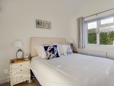 A bedroom with a double bed nightstands with lamps and a window with striped curtains at Outlook Lodge in Bowleaze