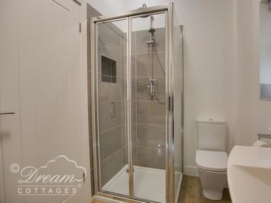 A bathroom with a glass shower enclosure a toilet and a sink at Outlook Lodge in Bowleaze