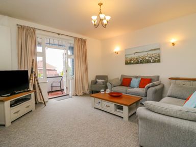 A living room with sofas cushions coffee table tv and door to balcony at Ocean Watch 1 in Greenhill