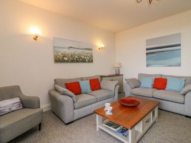 A living room with two sofas and an armchair a wooden coffee table and wall art at Ocean Watch 1 in Greenhill