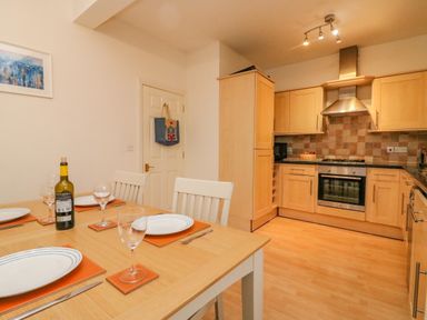 A kitchen with wood cabinets and a dining table set with plates and glasses at Ocean Watch 1 in Greenhill