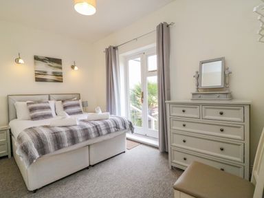 A bedroom with a bed with pillows and rolled towels a chest of drawers with a mirror and a window with curtains at Ocean Watch 1 in Greenhill