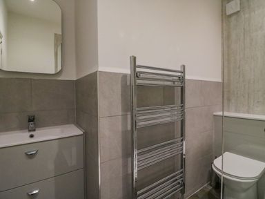 A bathroom with a sink cabinet mirror toilet and heated towel rail at Ocean Watch 1 in Greenhill