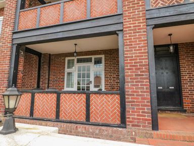An exterior view of a brick building with a covered porch and dark wooden beams at Ocean Watch 1 in Greenhill