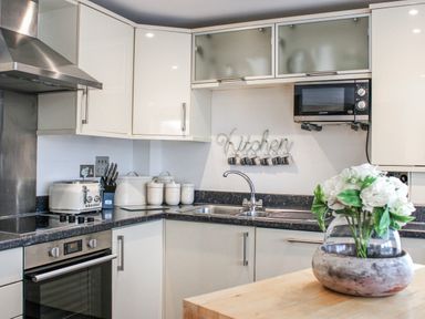 A kitchen featuring cabinets, sink, microwave, and a flower vase at Estuary View, Kingsbridge